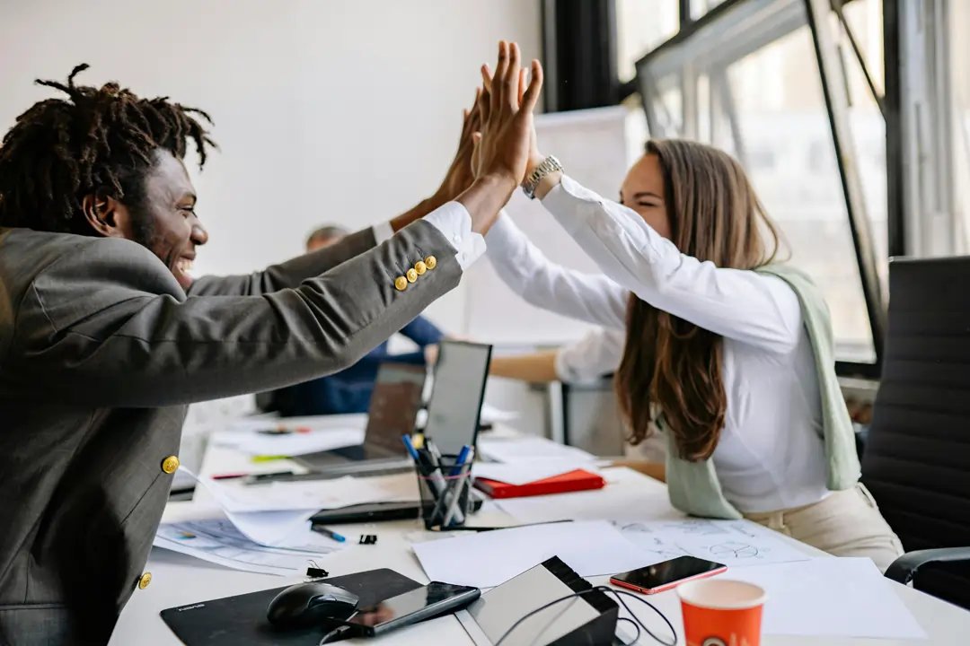 Due collaboratori esultano in azienda dandosi il cinque alto. Simbolo di un clima super positivo in azienda | 4Humans