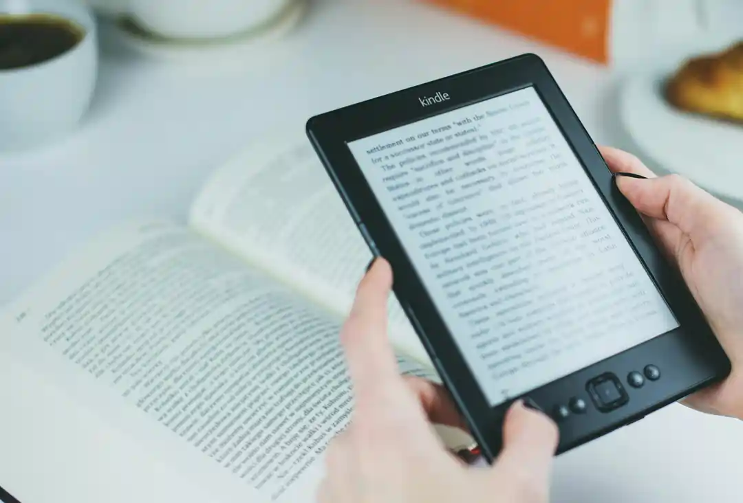 Kindle e libro di crescita personale aperti entrambi sul tavolo | 4Humans